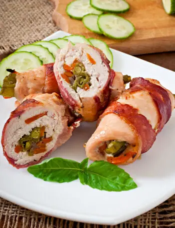 Stuffed chicken breasts wrapped in crispy pancetta served on a dinner plate